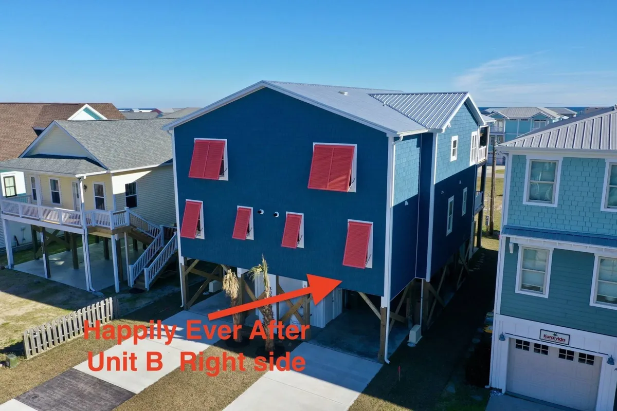 The bright blue exterior of a raised townhome with red shutters, surrounded by a playful, inviting atmosphere. The raised porch area hints at space for evening barbecues, family gatherings, and relaxation under the stars.